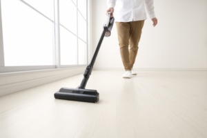 白い床に掃除機をかけている